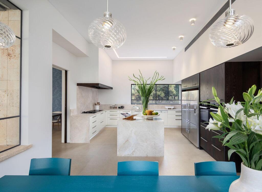 The kitchen pairs light and dark tones, with a turquoise dining table for everyday meals (Photo: Ori Ackerman) וילה בשפלה, עיצוב: איתמר לוי