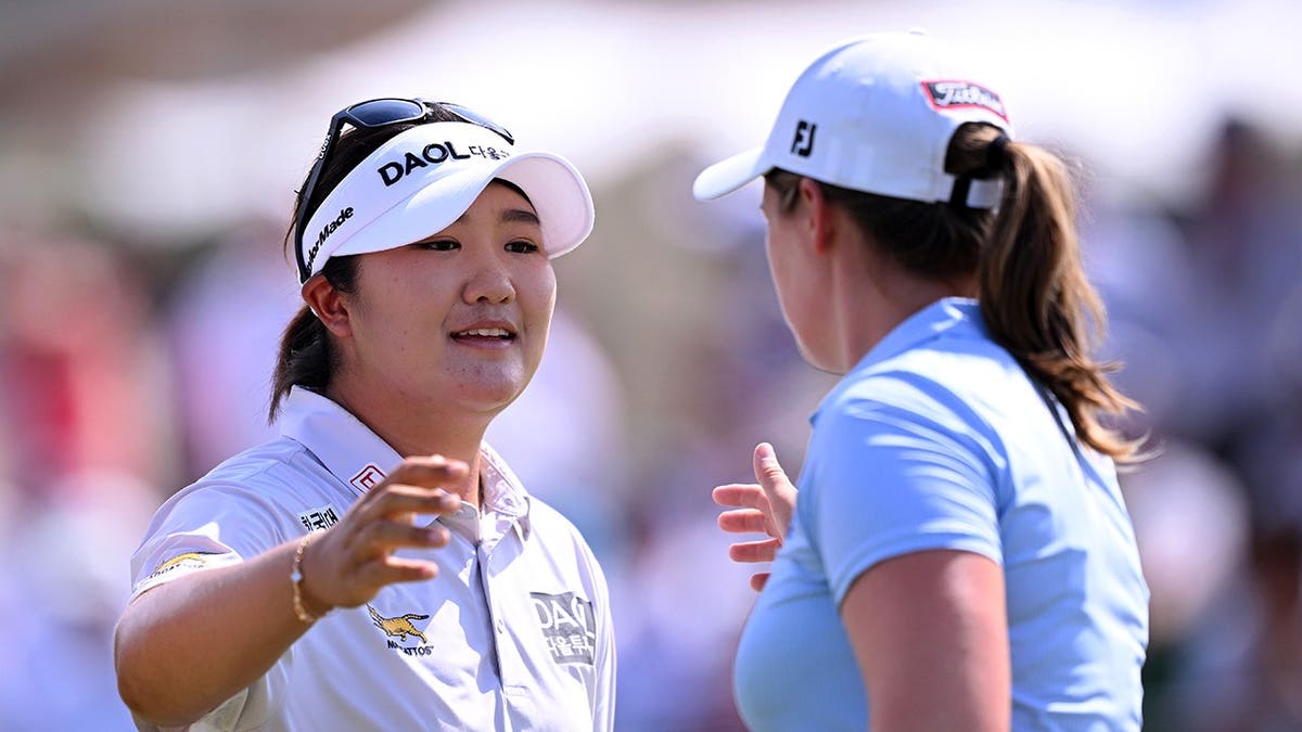 Haeran Ryu and Lottie Woad interact on the 18th green in Evian-les-Bains, France.