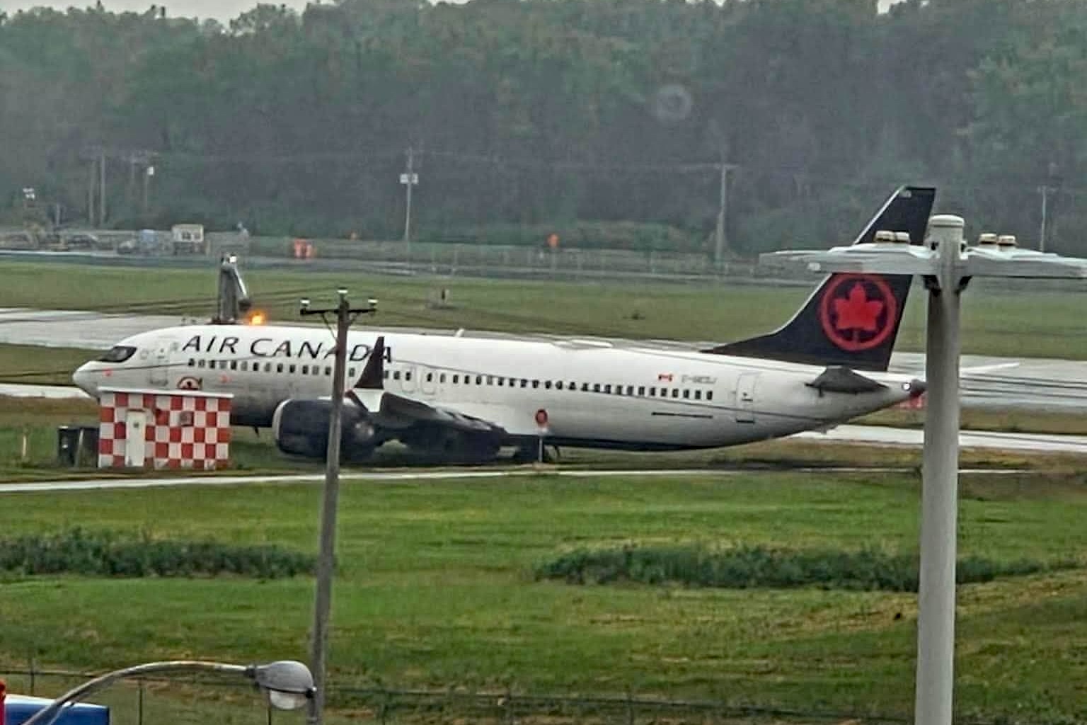 An Air Canada jet is visible in the grass at an airport.