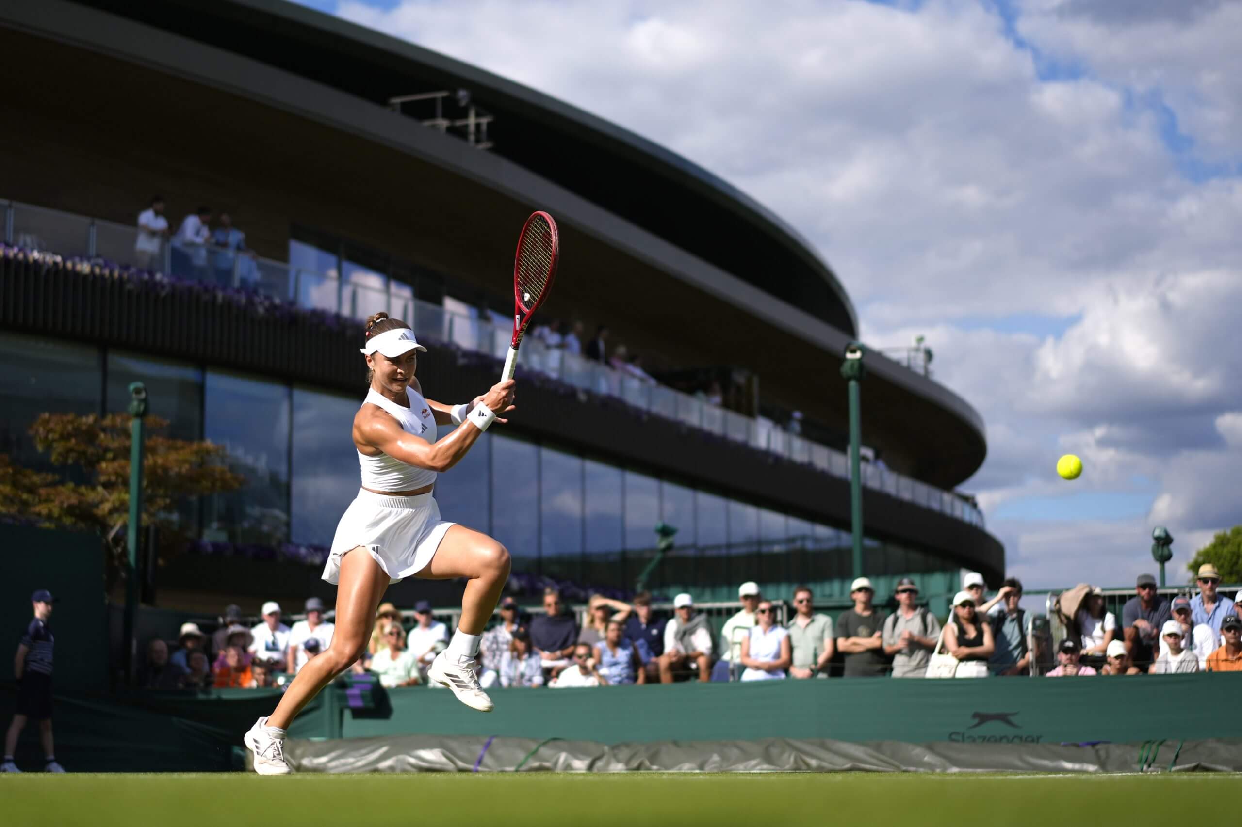 Iva Jović moves forward to hit a forehand on grass.