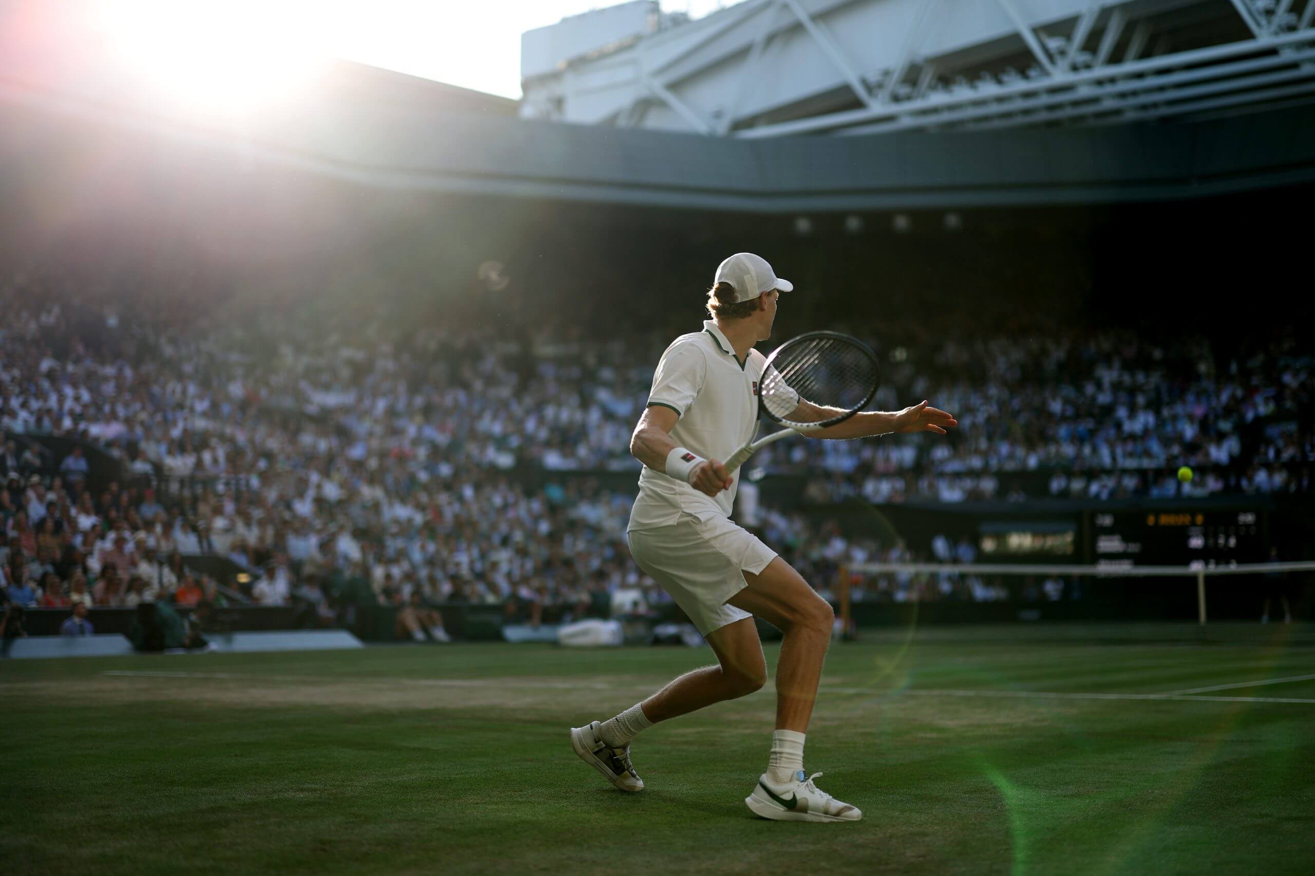 Jannik Sinner prepares to hit a forehand on a sun-splashed Centre Court.