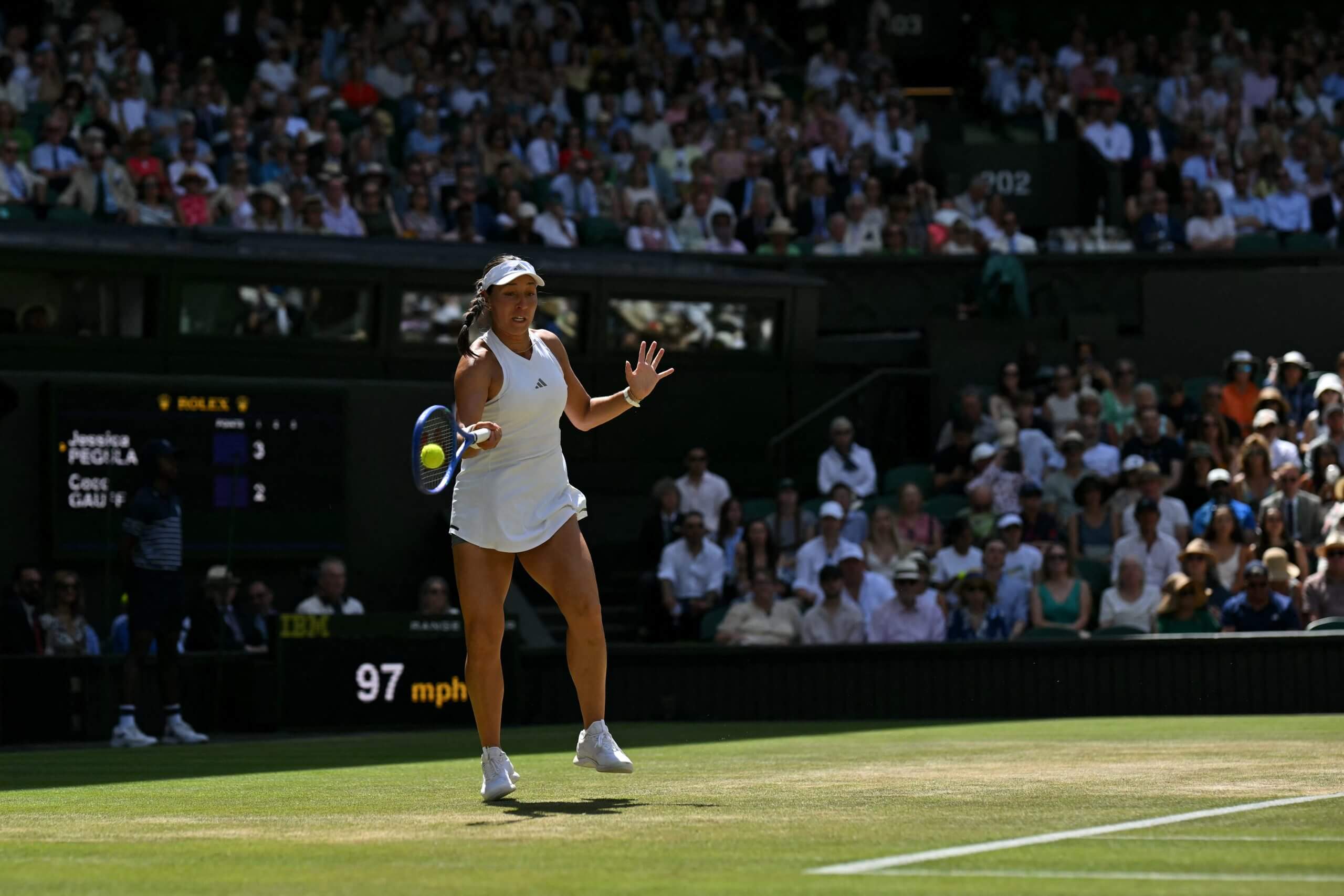 Jessica Pegula hits a forehand from well behind the baseline on a grass court.