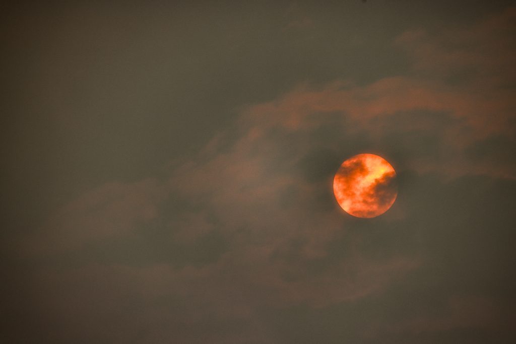 A bright orange sun is shrouded by wildfire smoke.