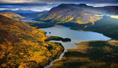 An aerial photo shows a river valley flanked on either side by fall foliage.