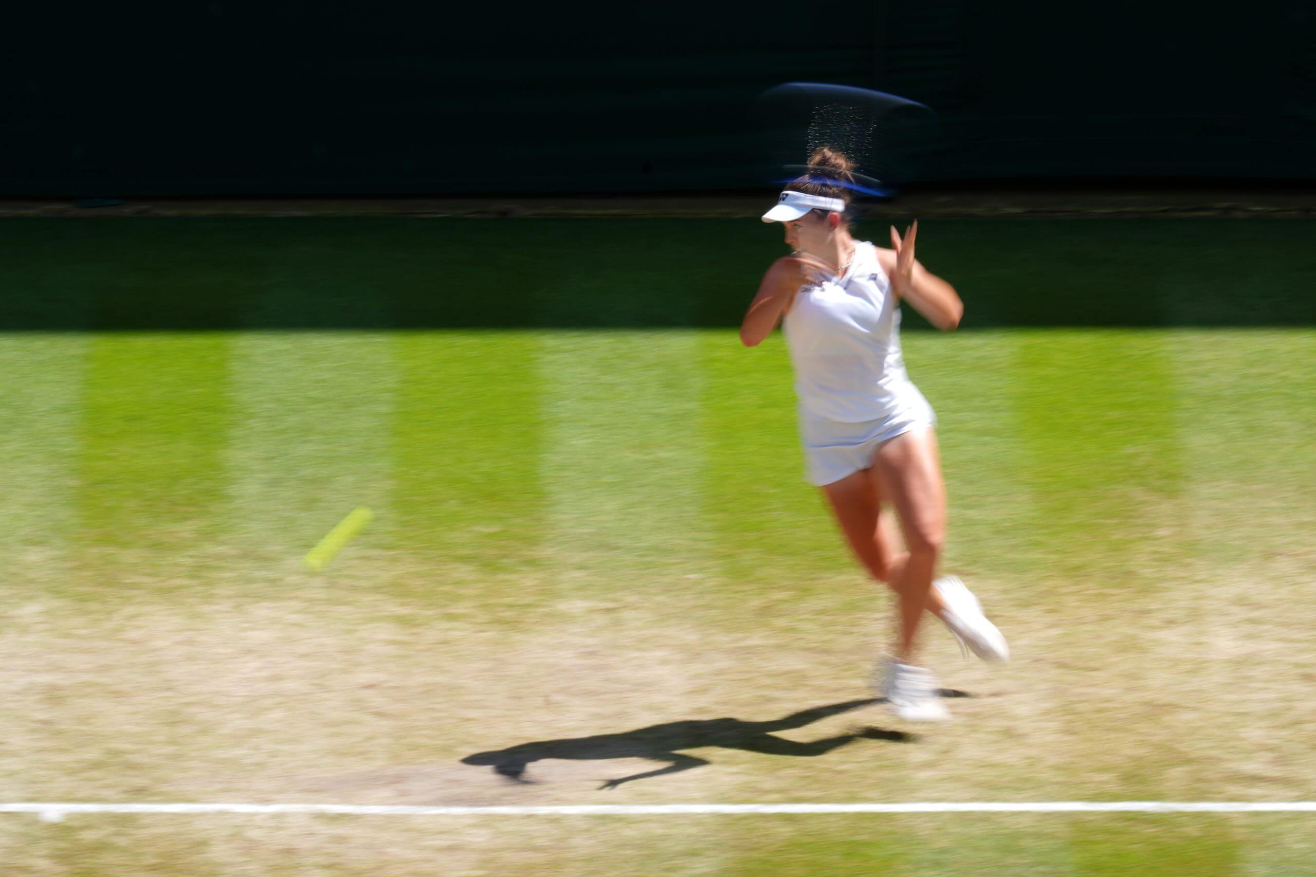 Linda Nosková hits a forehand on a grass tennis court in a long-exposure photo.