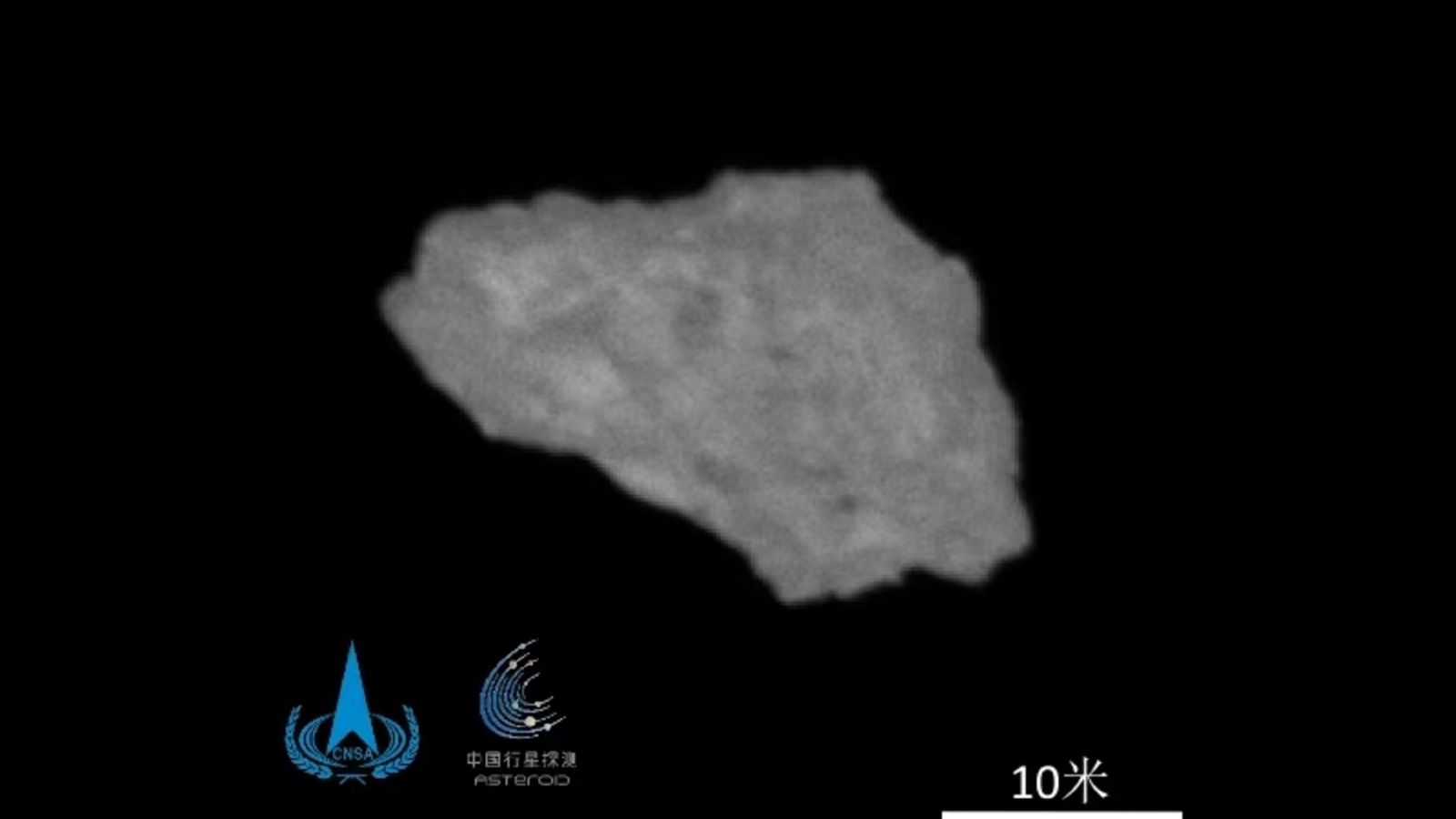 A blurry photo of a grey asteroid in the vacuum of space with Chinse logos superimposed on top