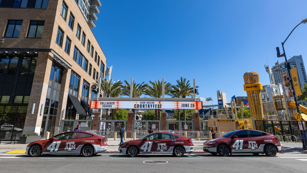 Three wrapped Ubers, looking like the Texas A&M branded NASCAR vehicle, on the streets of San Diego