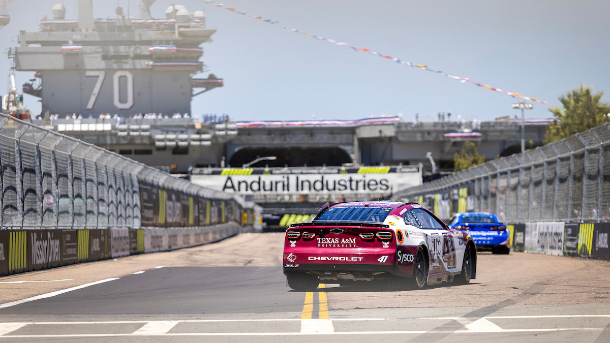 The Texas A&M branded NASCAR vehicle, a tribute to George H.W. Bush, is seen from the back as it speeds down the track in San Diego's military installation