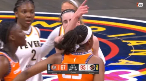 Caitlin Clark points at the scoreboard during a clash with WNBA rival Saniya Rivers