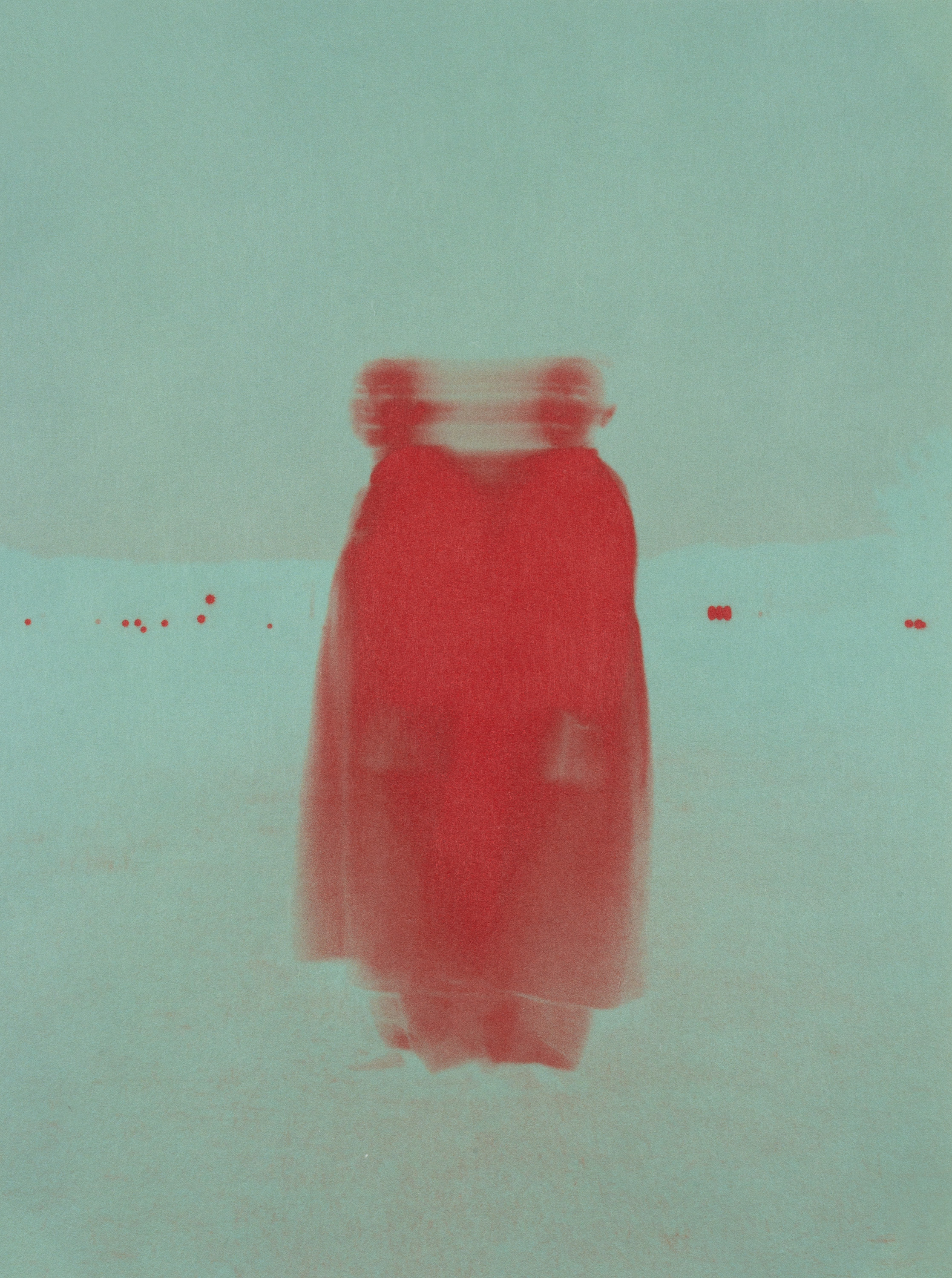 Blurred colour photograph of a red-robed figure against a pale teal background, their head doubled by motion to suggest movement.