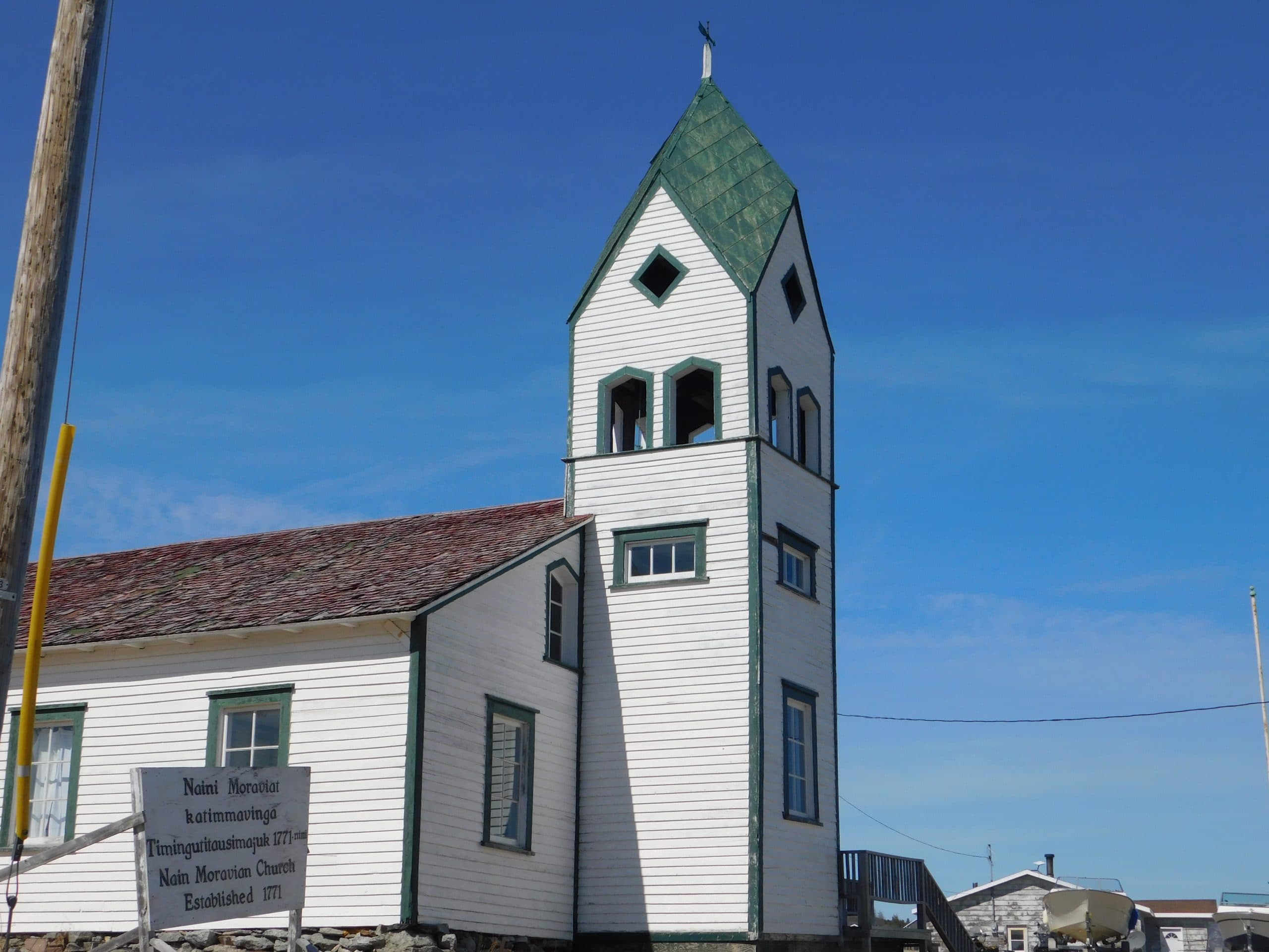 The Moravian church in Nain. It has white siding with green accents.