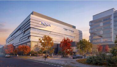Modern building with Nokia logo, featuring geometric design and large windows, surrounded by autumn trees at sunset, evoking a calm, innovative atmosphere.