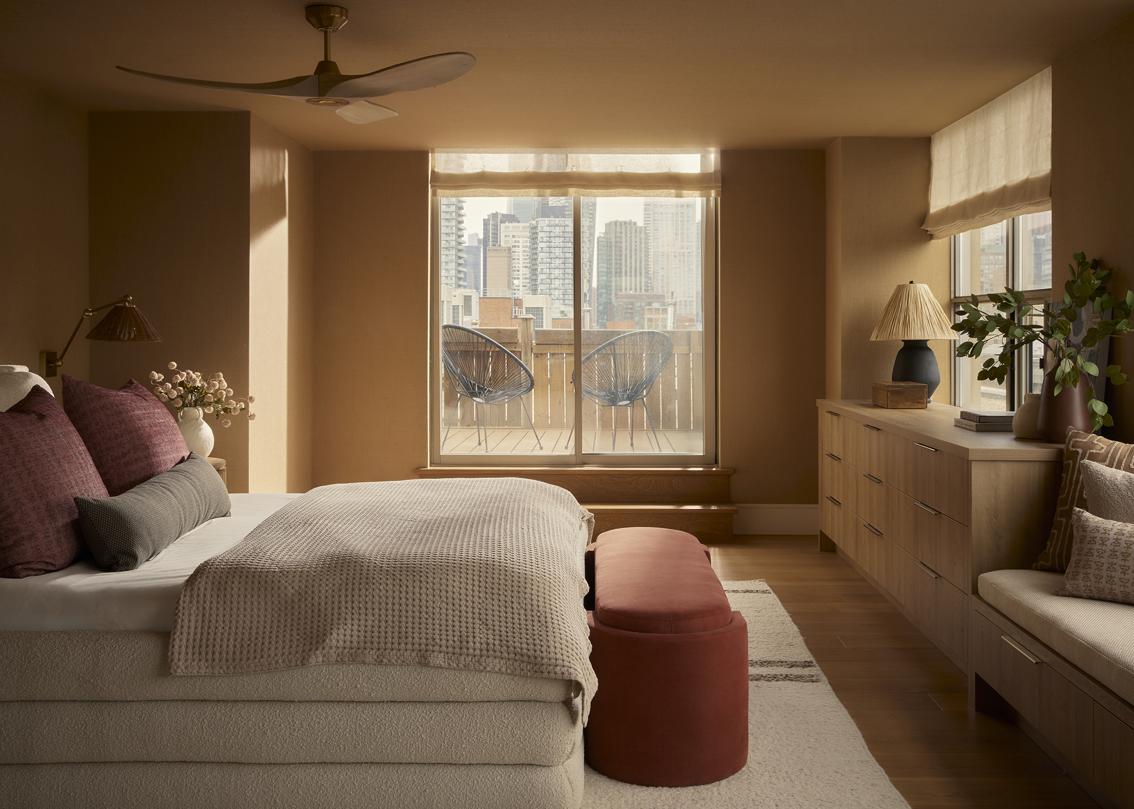 The primary bedroom embraces a calm, earthy palette and soft natural textures, opening onto a private balcony that extends the home's seamless connection between indoor comfort and outdoor living.