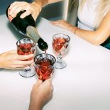 Unrecognizable female friends celebrate and drink red sparkling wine