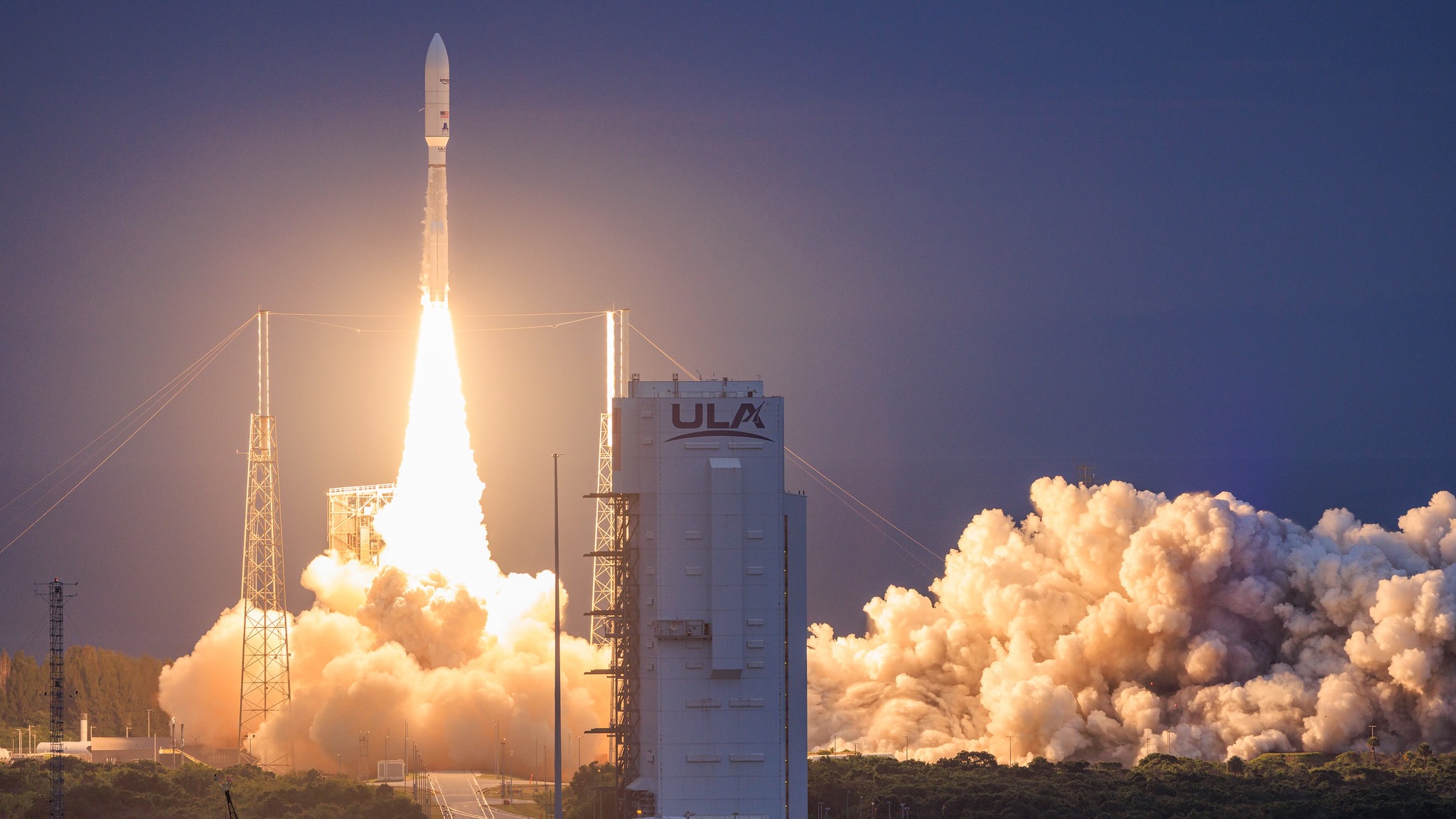 a big white rocket launches into a twilight sky