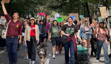 A group of people hold signs and walk down a residential street in Vancouver.