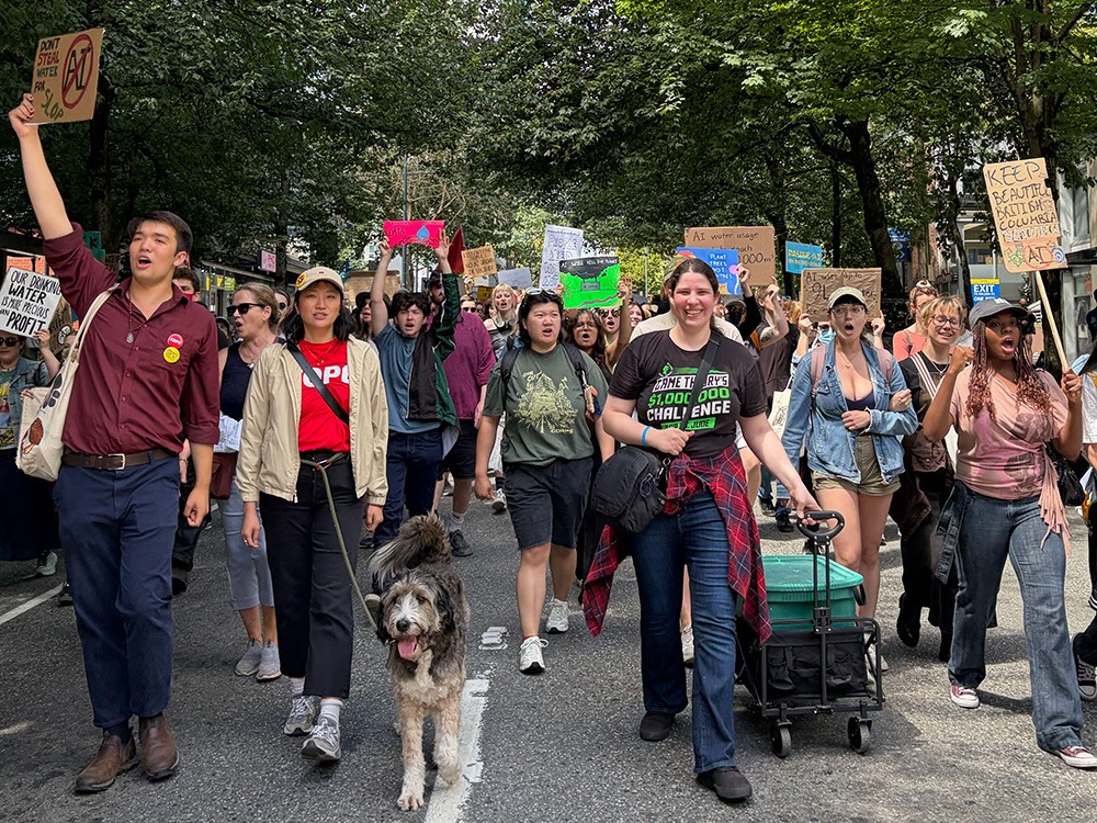 A group of people hold signs and walk down a residential street in Vancouver.