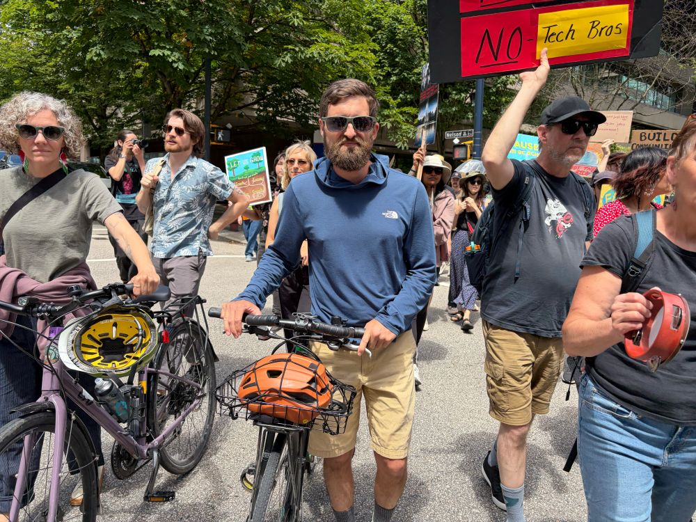 A group of people hold signs and walk down a residential street in Vancouver.