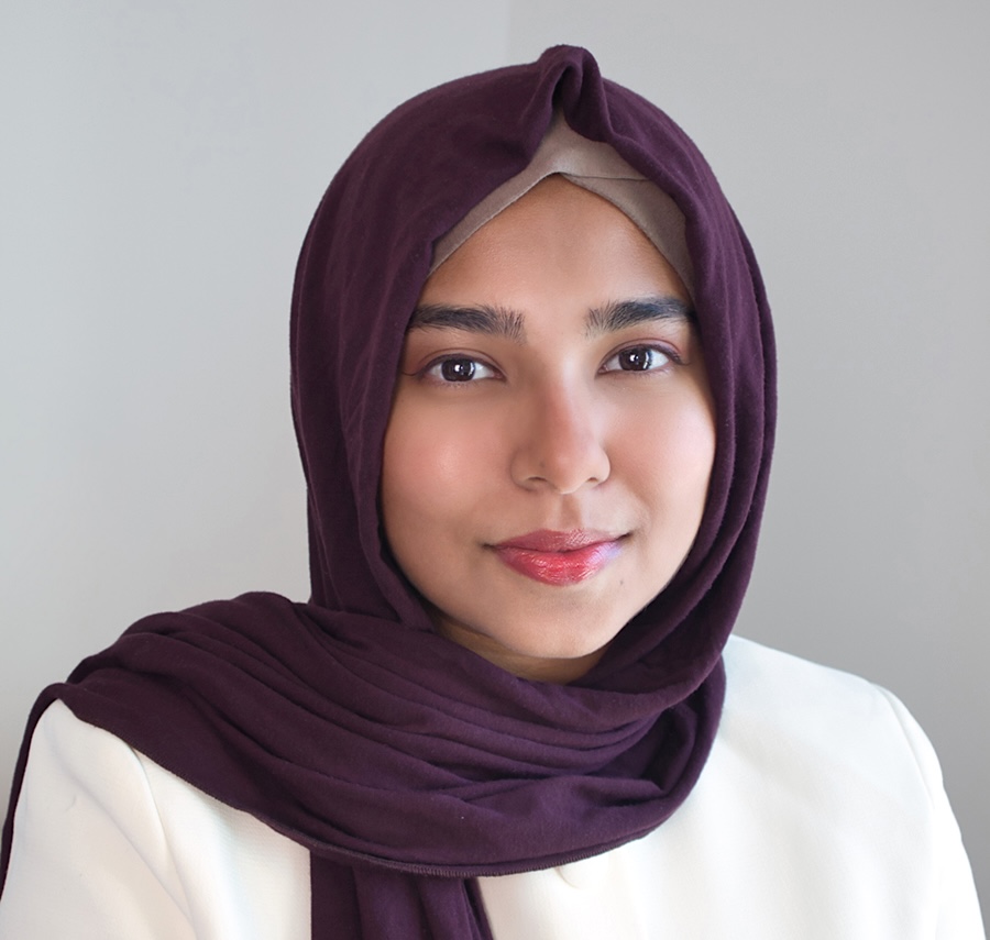 A woman with medium skin tone wears an eggplant-coloured hijab.