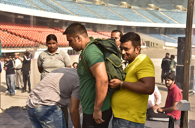 a man wearing a yellow t shirt puts a backpack on rohtash