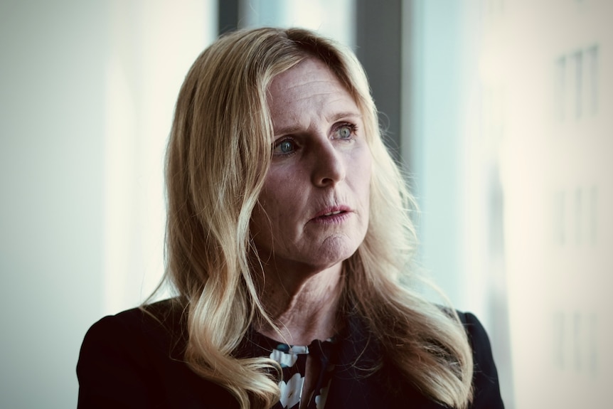 A close-up shot of ASIC commissioner Simone Constant at her Sydney office. She has long blonde hair and wears a black jacket.