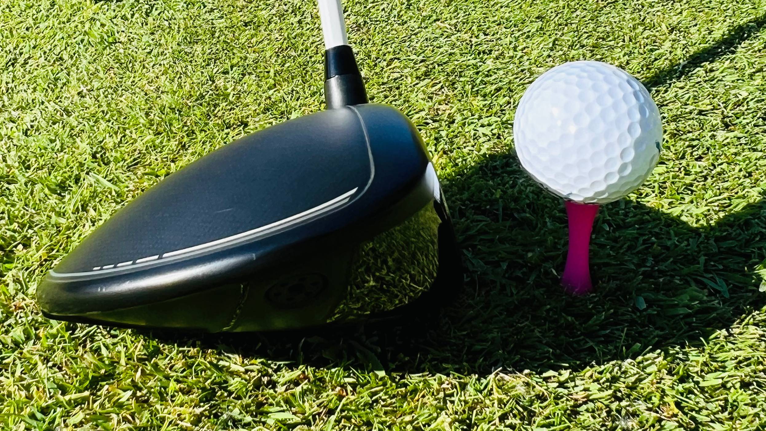 Driver addressing ball on pink 'castle' tee