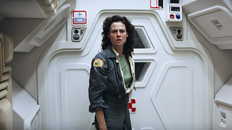 Sigourney Weaver as Ellen Ripley in Alien, standing in front of a closed door on the Nostromo.