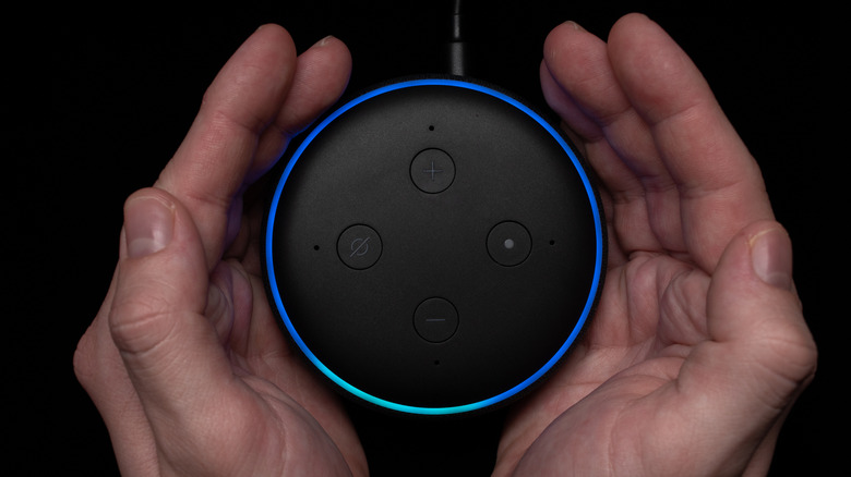 A pair of hands around the Amazon Echo Dot