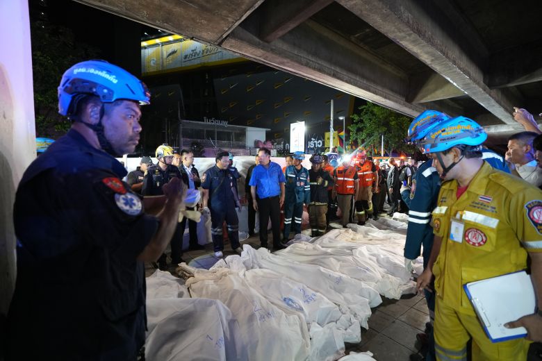 Thai Prime Minister Anutin Charnvirakul, in blue, inspects the site of a fire as bodies of victims are laid in a row in Bangkok, Thailand, Monday, July 13, 2026.