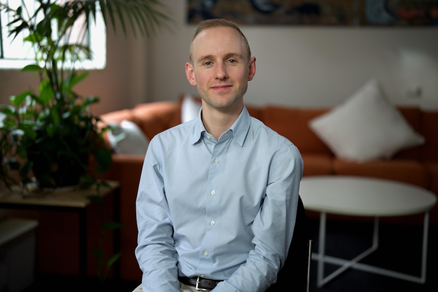 Matthew Bowes seated in front of a couch