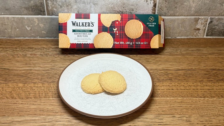 Walker's Shortbread Cookies box leaning on a backsplash with two cookies on a white plate