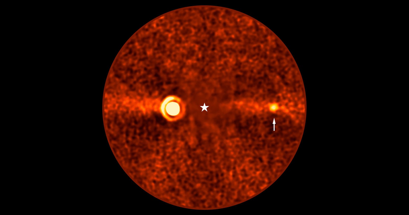 Orange-hued, grainy circular image of a star at the center with a glowing ring to the left and a smaller bright spot to the right, indicated by an arrow. The background is dark with scattered noise.