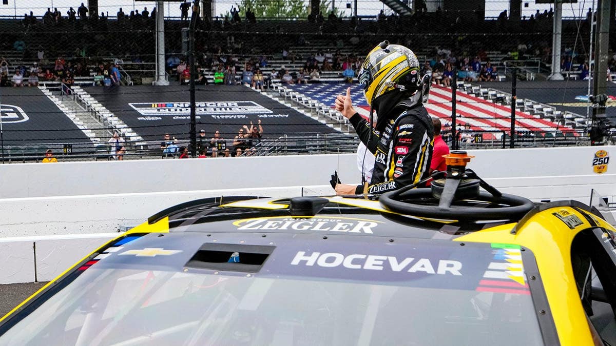 Carson Hocevar gives a thumbs up to fans during NASCAR qualifying at Indianapolis Motor Speedway.