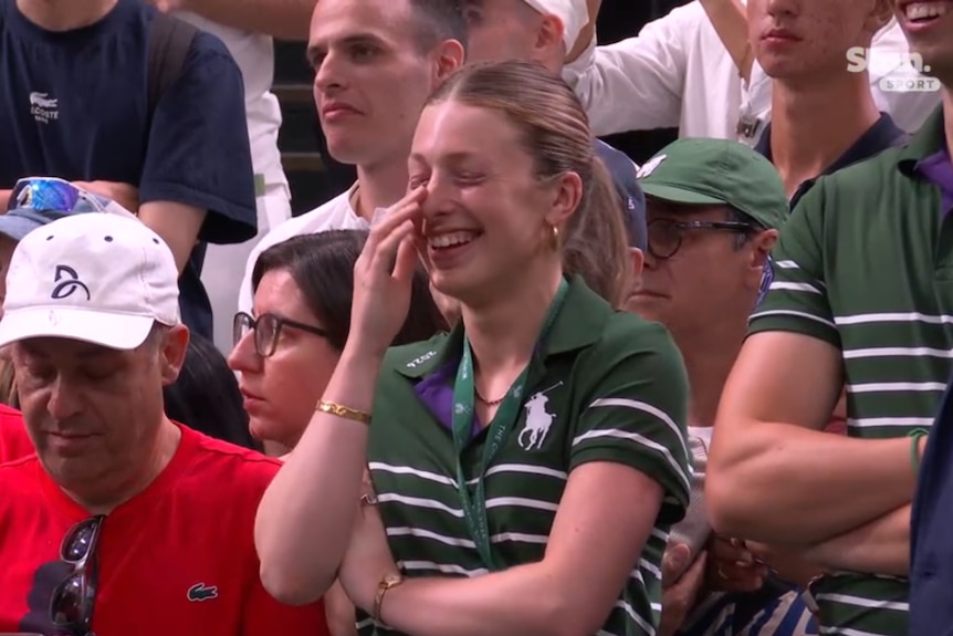 A ball kid laughs courtside at Wimbledon after Novak Djokovic's match.