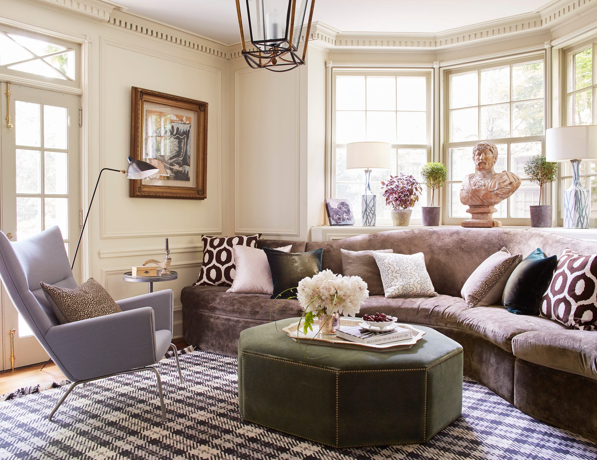 Elegant living room featuring a curved sofa, modern decor, and natural light from large windows.