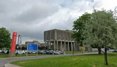 The exterior of hospital grounds with an emergency sign to the left.