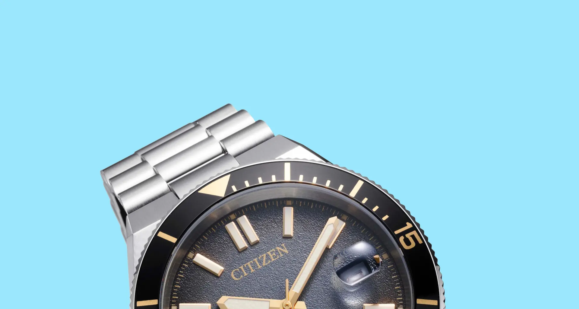 Close-up of a Citizen watch with a black bezel, gold-tone markers, and a stainless steel bracelet on a blue background.