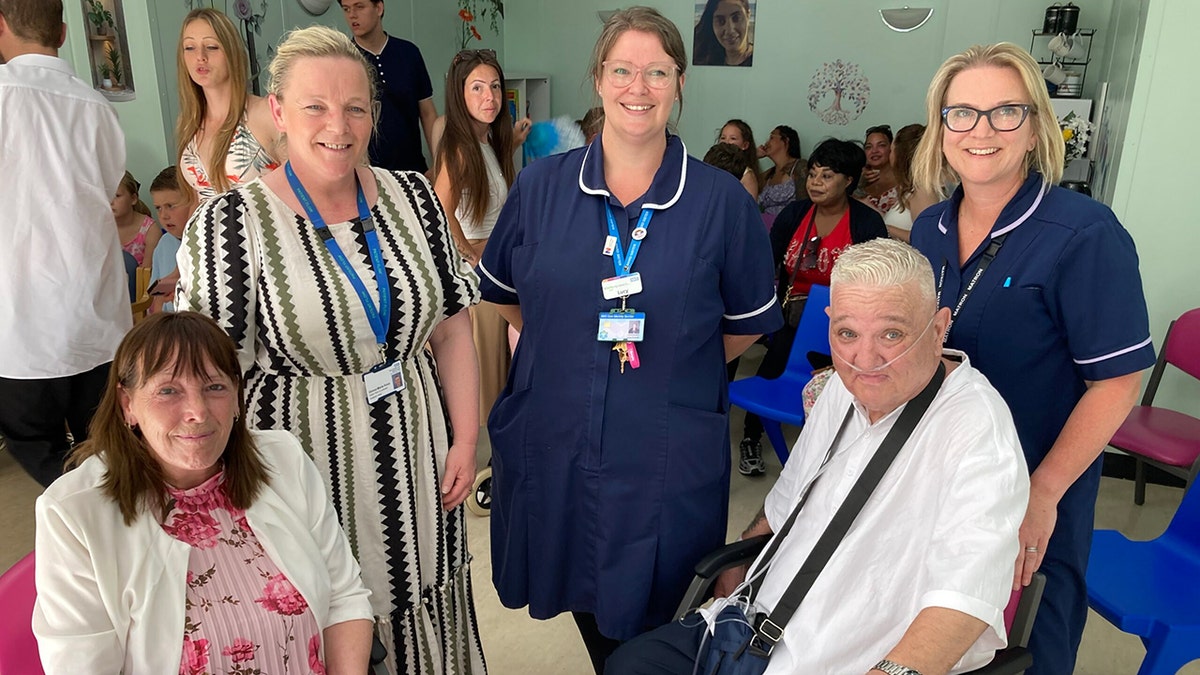 Dean Pennell and Kay Beaman with nurses at a hospital.