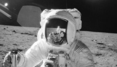 NASA's Apollo 12 mission photo shows an astronaut on the Moon's surface holding a container of lunar soil, with the other astronaut reflected in his helmet visor (Credit : NASA)