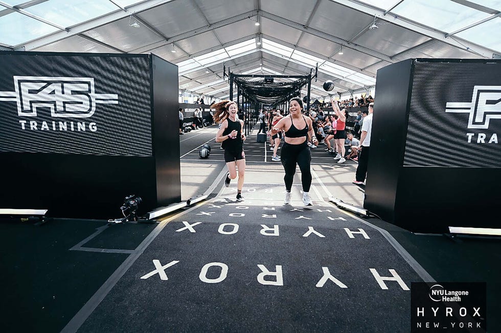 Two women running towards the camera in a fitness training event inside a large tent. Two women running towards the camera in a fitness training event inside a large tent.