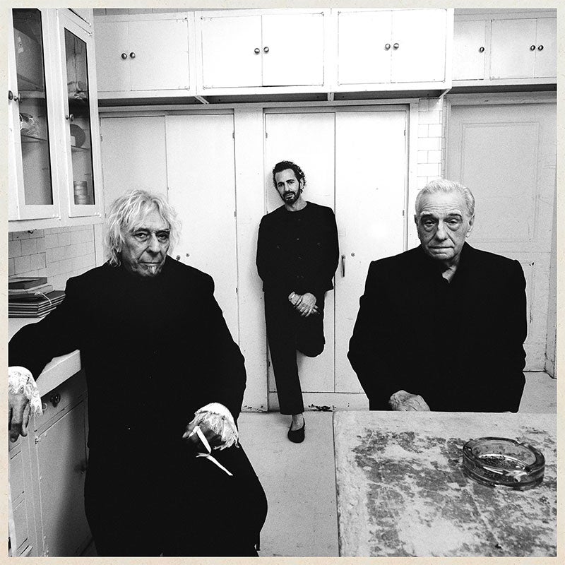 The cover of Charli XCX’s album Music, Fashion, Film as described in the text, with Martin Scorsese, Marc Jacobs, and John Cale. They're all just standing together in a kitchen.