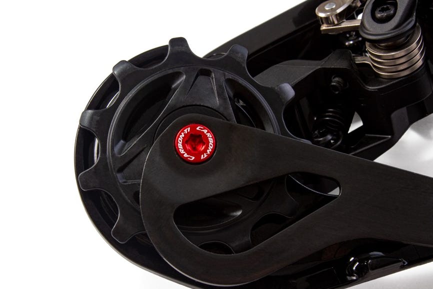 Close-up of a black bicycle drivetrain component featuring a red bearing and a polished finish.