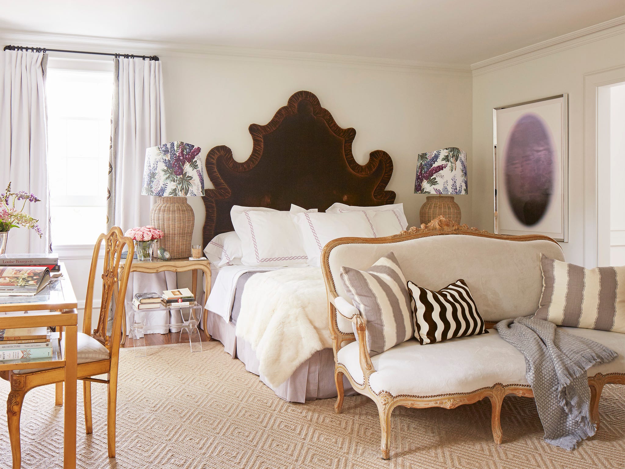 Cozy bedroom featuring an ornate headboard, decorative lamps, stylish sofa, and a welcoming atmosphere.