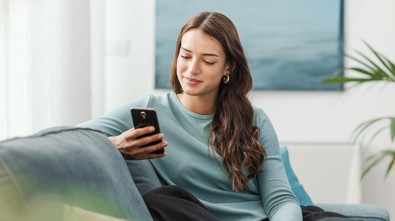 A woman using a phone while sitting on a coach