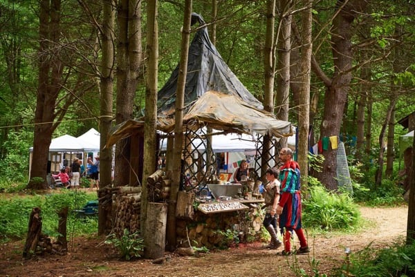 wooden artists' stall in a forest with several shoppers out front