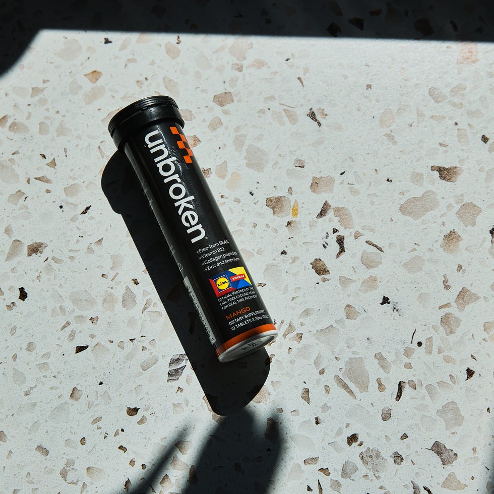 Black tube of Unbroken vitamin effervescents on a textured light surface, casting a shadow.