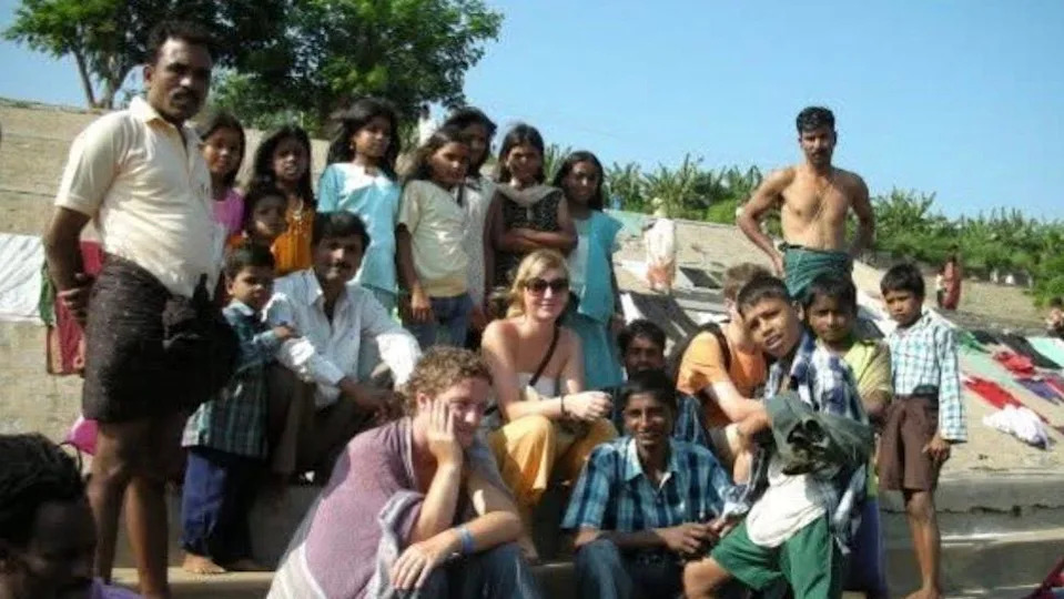 Lowri sitting on steps with a large group of locals in India