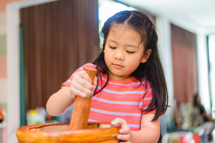 Girl using pestle and mortar.