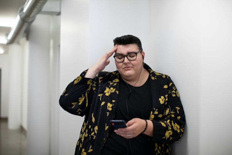 Person wearing glasses touches head, looking confused and upset.