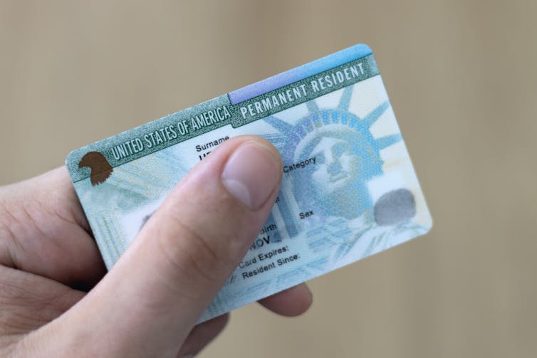 A person grasps a green card.